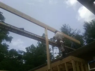 Carpenter setting a ridge beam over a new addition frame — Ice Dam Removal by Roofing Brothers in Faucett