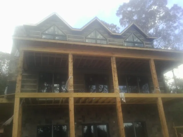 Dormers and porch framing on a large log home under construction — Roof Coating work by our crew in Faucett