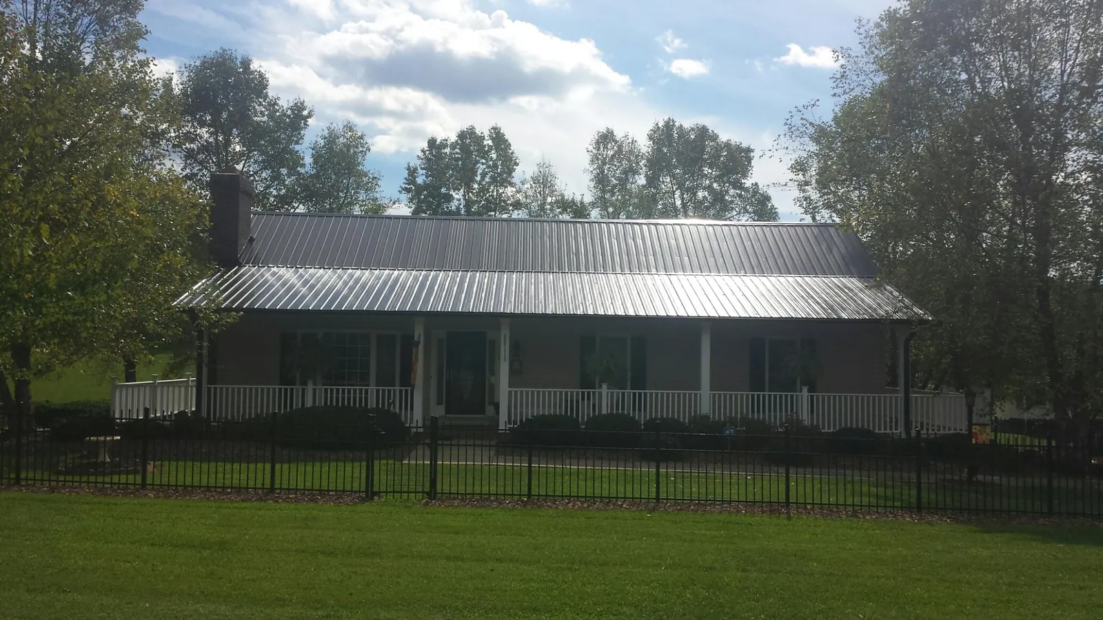 Gray metal roof on a brick ranch with a full width front porch — Gutter Guard Installation work by our crew in Faucett