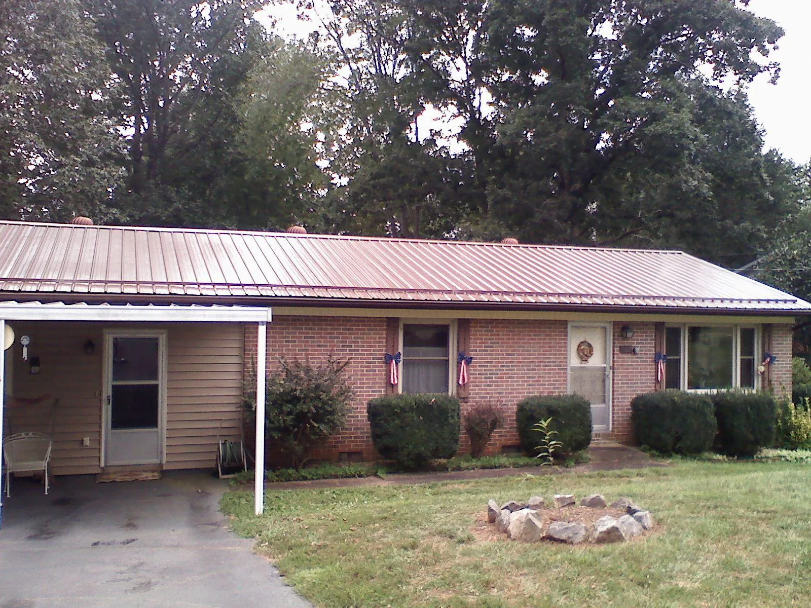 Bronze metal roof and carport on a brick ranch home — Roof Repair work by our crew in Faucett