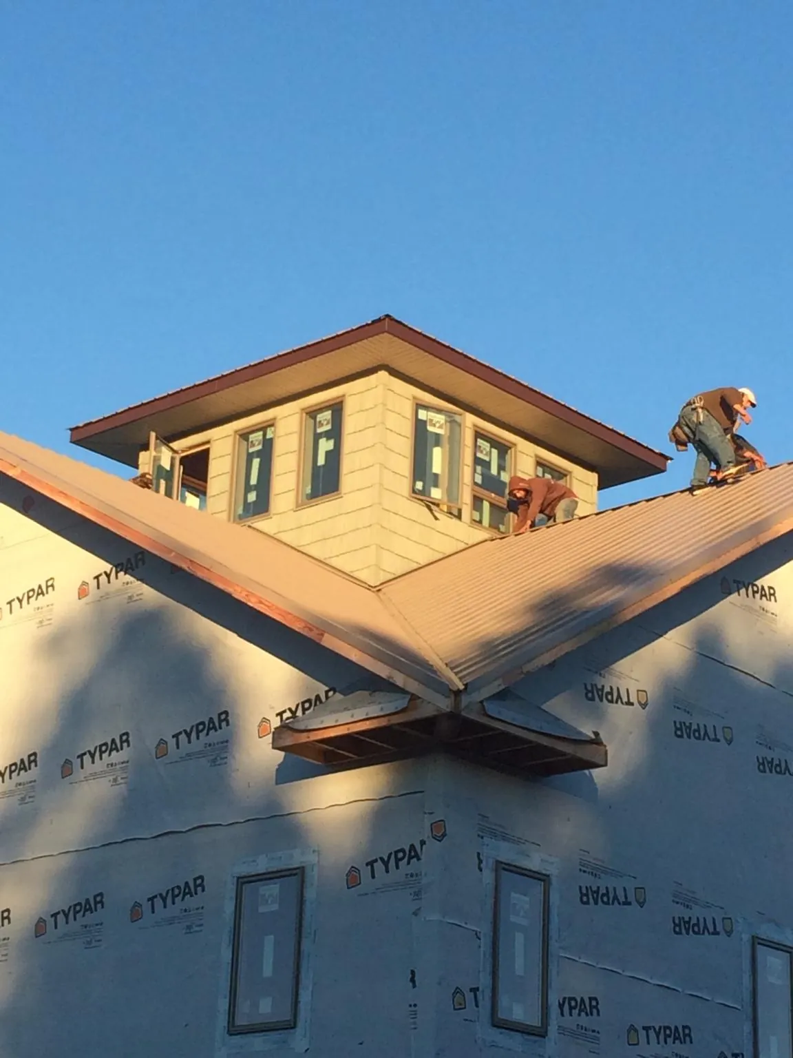 Roofers working around a rooftop cupola on a new metal roof at sunset — Roof Waterproofing in Faucett by Roofing Brothers